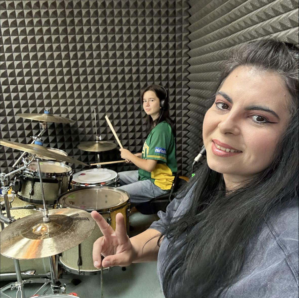 Raluca face un selfie în studio, cu o elevă la tobe în spate